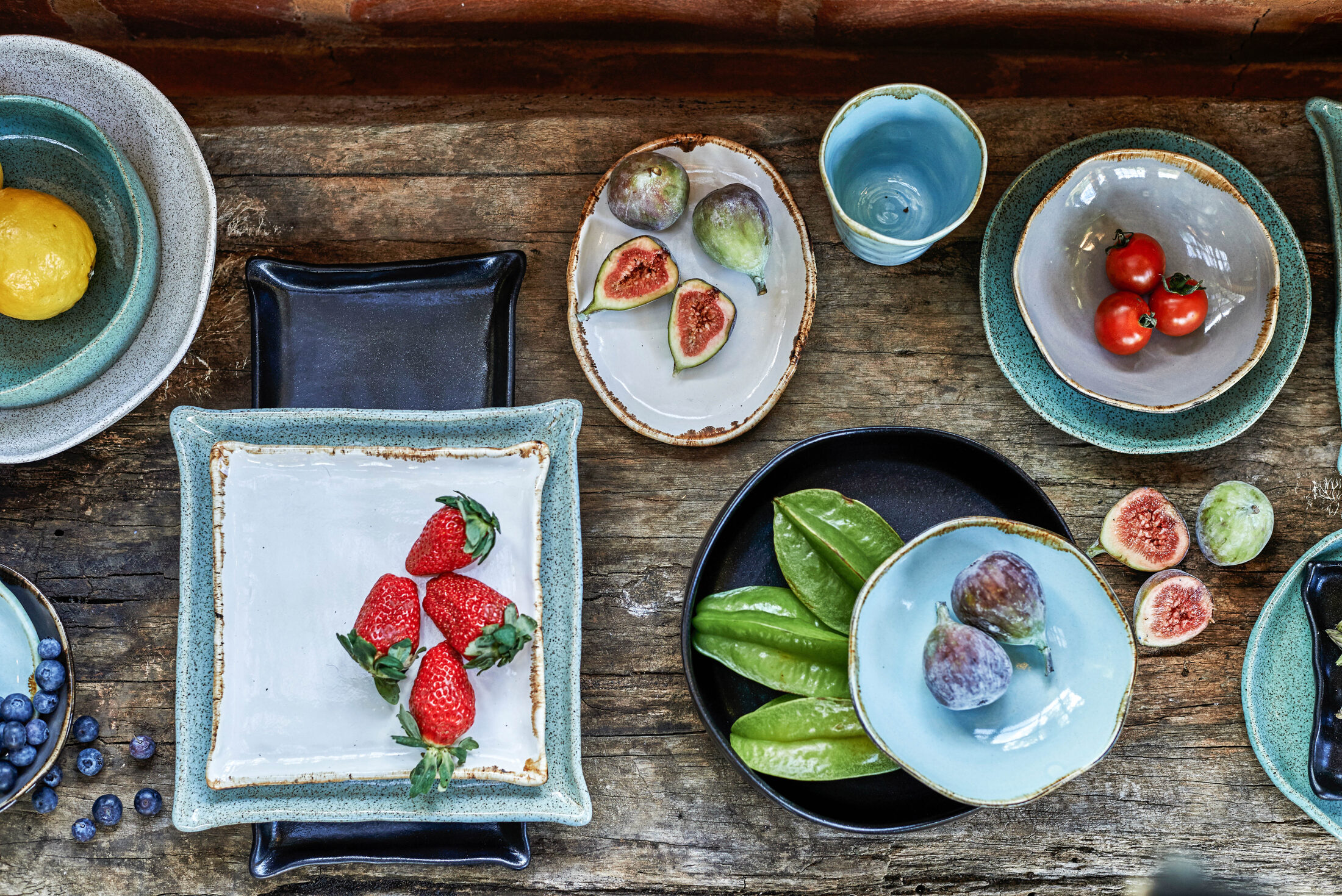 Mesa com cerâmicas artesanais e frutas vista de cima