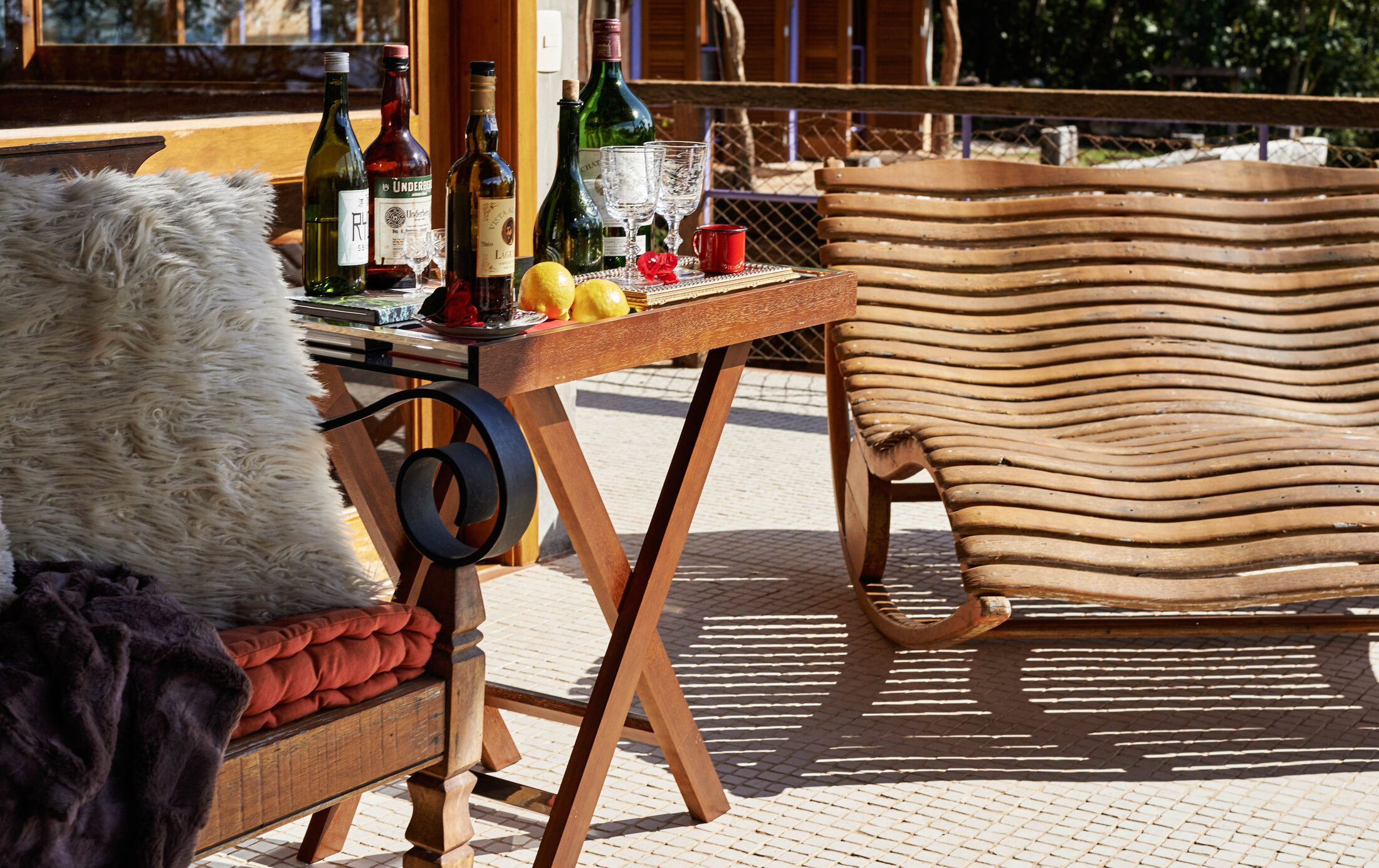 Terraço de pousada ao sol com mesa de bebidas e espreguiçadeira